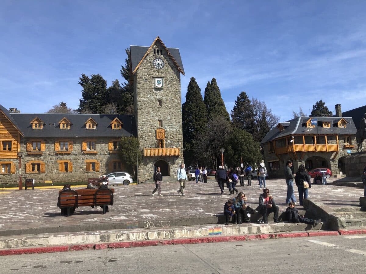 La torre del reloj del Centro Cívico de Bariloche, en piedra y madera, con la plaza adelante