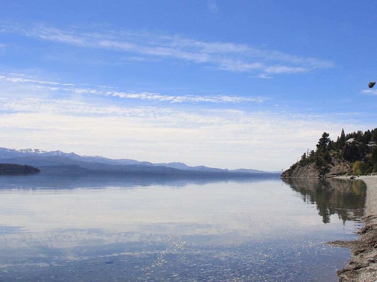 La orilla de canto rodado de Playa Bonita sobre el lago Nahuel Huapi, con las montañas al fondo